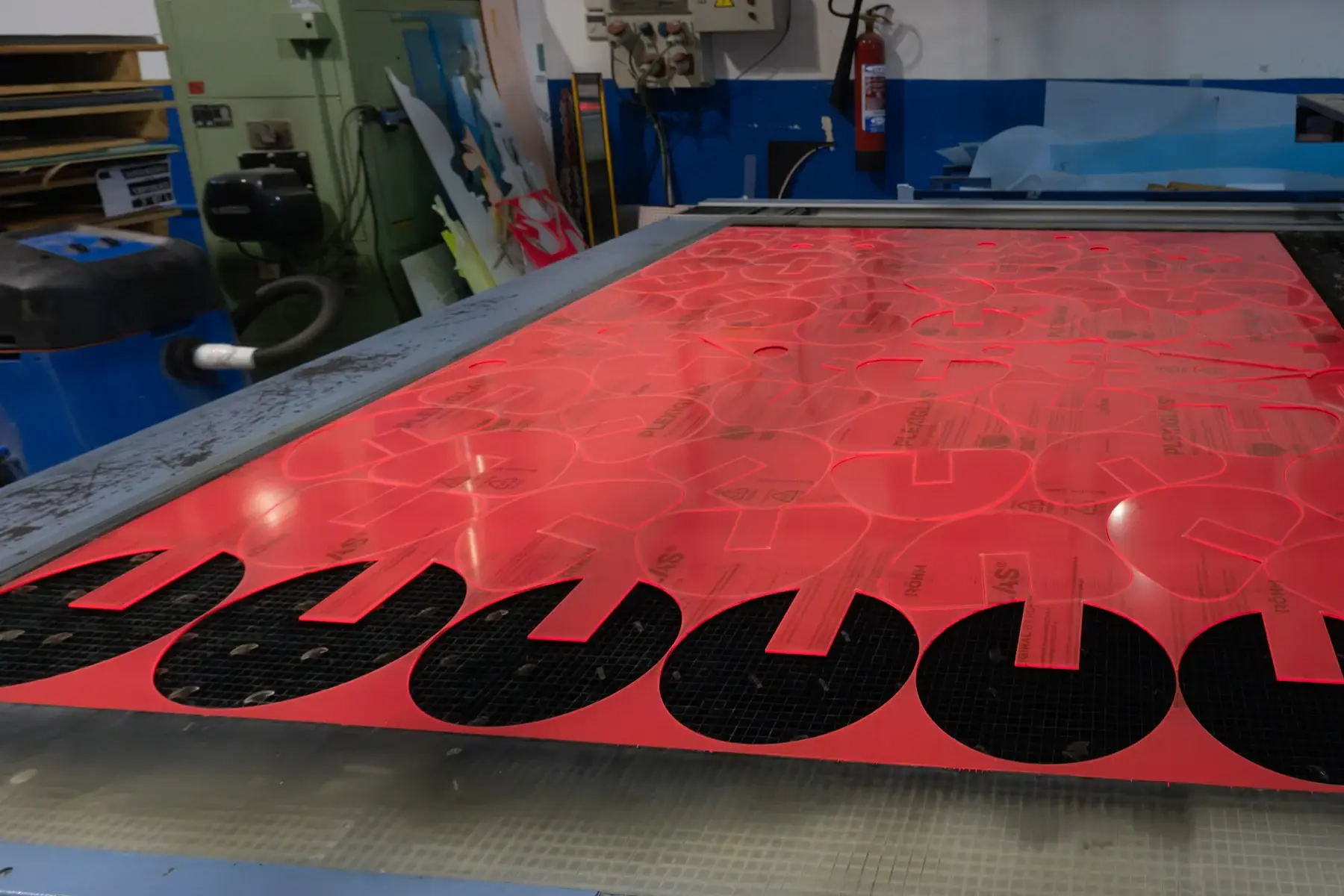 Corte de piezas de metacrilato rojo en el taller Neolaser